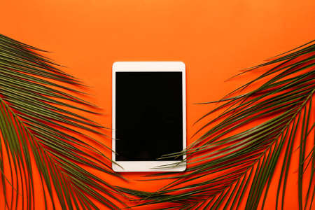 Modern tablet computer with tropical leaves on color backgroundの写真素材