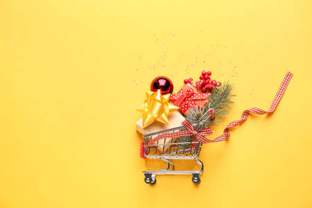 Shopping cart with Christmas decor on color backgroundの写真素材