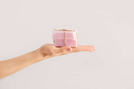 Female hand with soap bars on light backgroundの写真素材