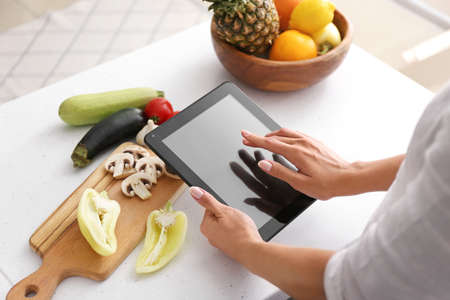 Woman with tablet computer cooking in kitchenの写真素材