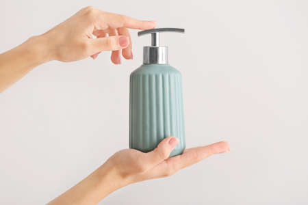 Female hands with soap in bottle on light backgroundの写真素材