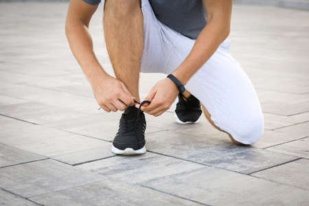 Handsome sporty man tying shoelaces outdoors