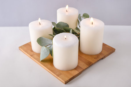 Beautiful candles with eucalyptus on light backgroundの写真素材