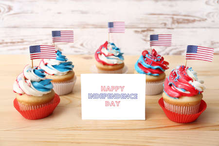 Tasty patriotic cupcakes and card for Independence Day on table