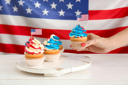 Woman taking tasty patriotic cupcake from tableの写真素材