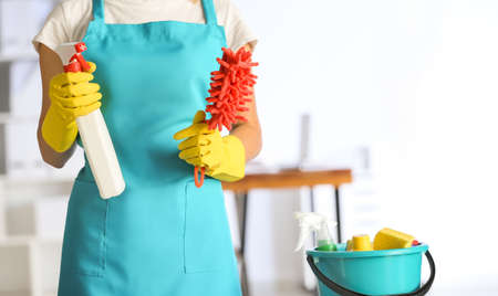 Female janitor with set of cleaning supplies in office
