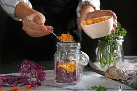 Woman preparing vegetables for fermentation at table, closeup