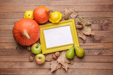 Autumn composition with fresh pumpkins and photo frame on wooden backgroundの写真素材