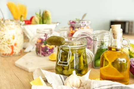 Jar with canned cucumbers on wooden table in kitchen