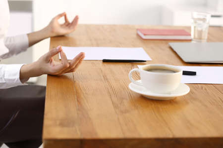 Young businesswoman meditating in office