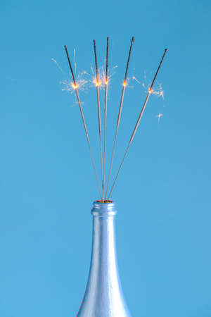 Bottle of champagne with festive Christmas sparklers on color backgroundの写真素材