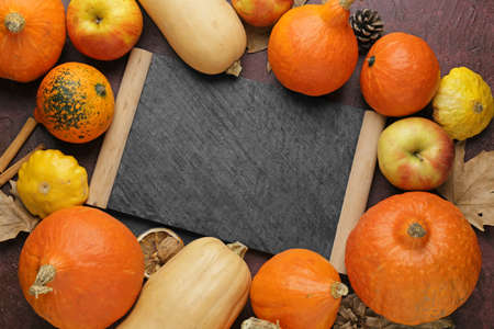 Autumn composition with fresh pumpkins and chalkboard on color background