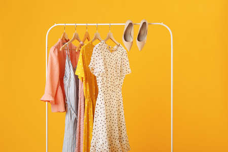 Rack with hanging clothes on color backgroundの写真素材