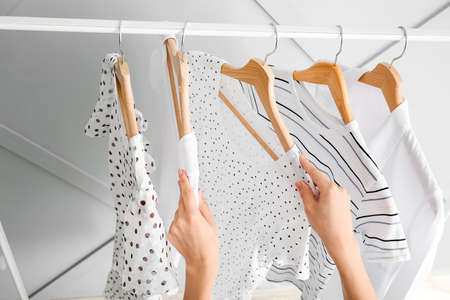 Woman near rack with hanging clothes indoors