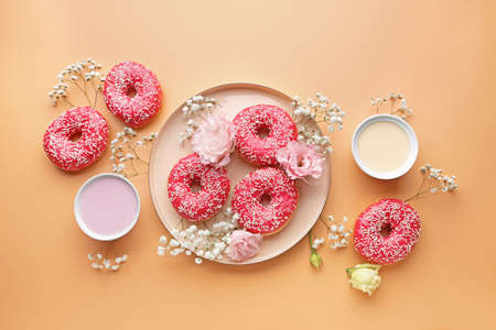 Composition with sweet tasty donuts and flowers on color backgroundの写真素材