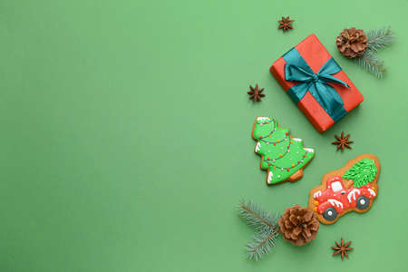 Tasty Christmas cookies with gift on color background