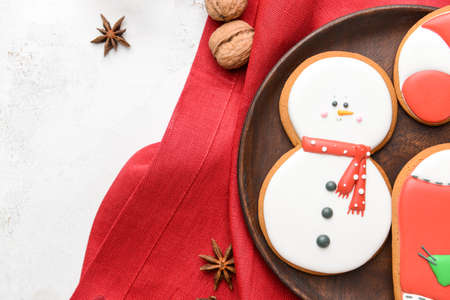 Plate with tasty Christmas cookies on light background