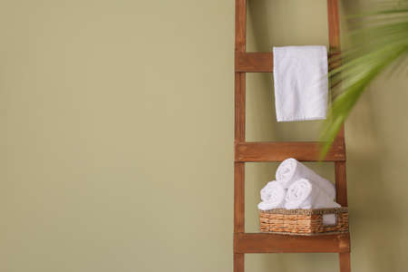 Clean towels on wooden ladder near color wallの写真素材
