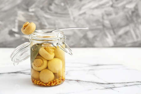 Jar with canned mushrooms on table