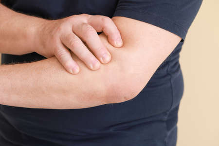 Senior man suffering from pain in elbow on light background, closeup