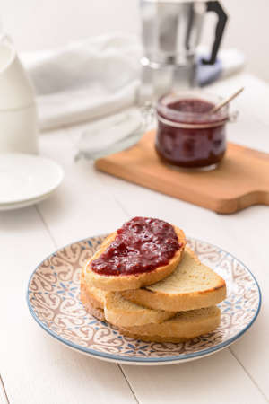 Plate with toasted bread and sweet jam on white table