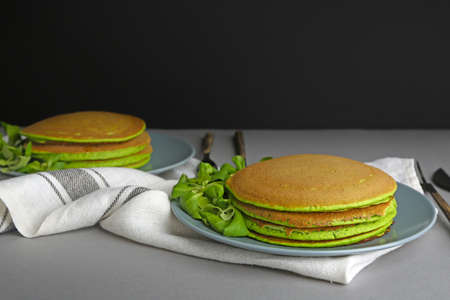 Tasty green pancakes on table