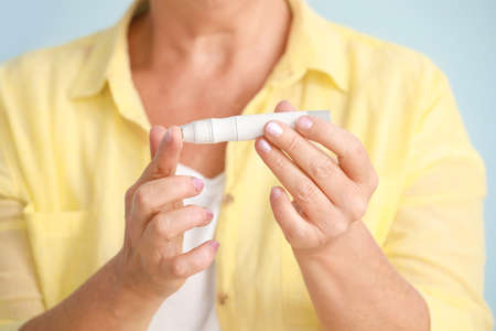 Diabetic woman taking blood sample with lancet pen, closeup