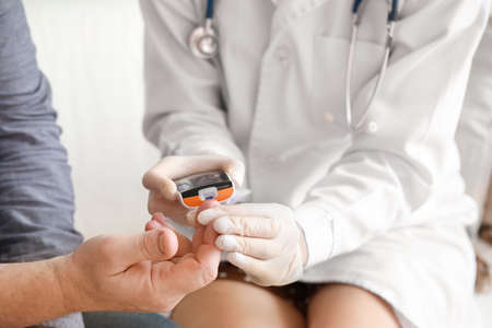 Doctor checking blood sugar level of diabetic patient in clinic, closeupの写真素材