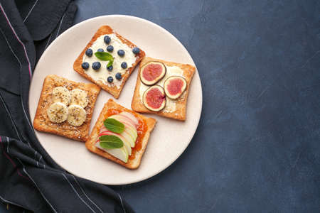 Plate with tasty sandwiches on dark background
