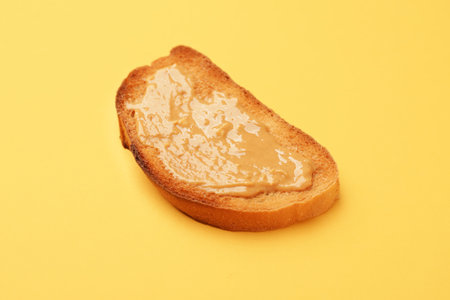 Tasty toasted bread with peanut butter on color background