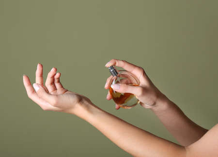 Beautiful young woman with bottle of perfume on color backgroundの写真素材