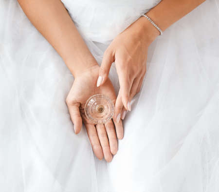 Beautiful young bride with bottle of perfume at home