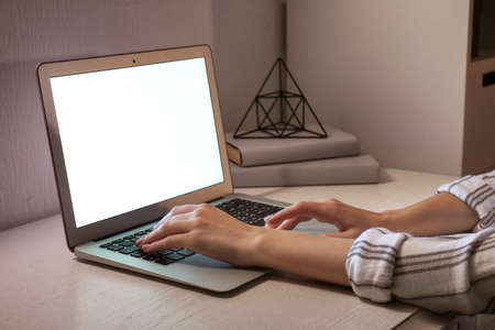 Woman working on laptop at table in eveningの写真素材