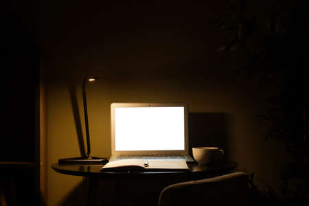 Modern workplace with laptop in eveningの写真素材