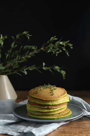 Plate with tasty green pancakes on tableの写真素材