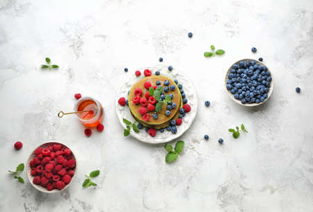 Plate with green pancakes, fresh berries and honey on light backgroundの写真素材