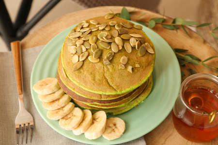 Plate with tasty green pancakes and honey on tableの写真素材