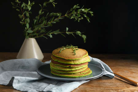 Plate with tasty green pancakes on tableの写真素材