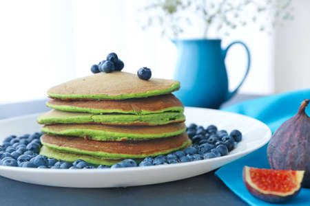 Plate with tasty green pancakes and berries on table