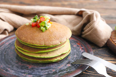 Plate with tasty green pancakes on tableの写真素材