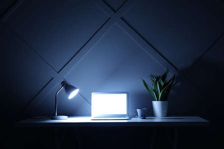 Modern workplace with laptop in eveningの写真素材