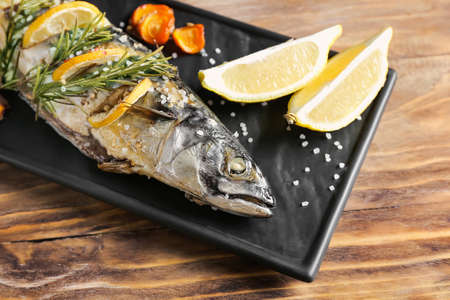 Plate with baked mackerel fish on wooden tableの写真素材