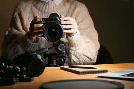 Female photographer working at table in evening, closeupの写真素材