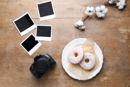 Tasty donuts with photo camera on wooden backgroundの写真素材