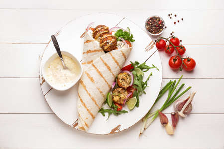 Board with tasty falafel pita and sauce on white wooden table