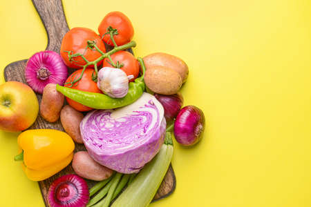 Board with many healthy vegetables on color backgroundの写真素材