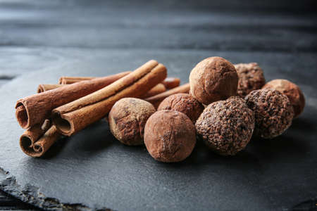 Tasty sweet truffles with cinnamon on slate plate, closeup