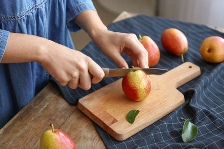 Woman cutting fresh pears at table, closeupの写真素材