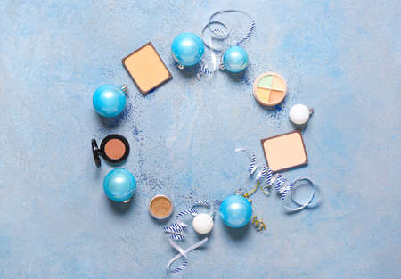 Frame made of cosmetics with Christmas decor on color background