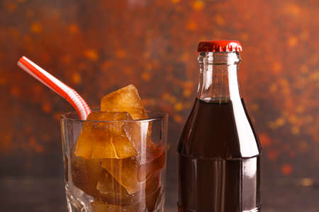 Bottle and glass of cold cola on color backgroundの写真素材